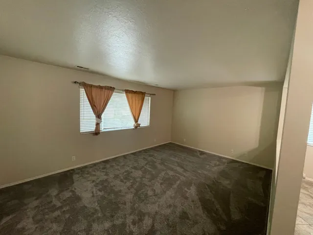 Unfurnished room featuring dark colored carpet and baseboards