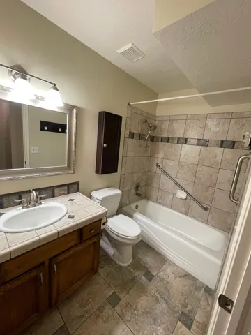 Bathroom with vanity, washtub / shower combination, and a textured ceiling