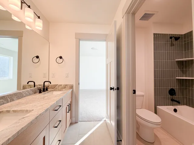 Jack and Jill Full bath with double vanity, light tile patterned floors, tub / shower combination, and light carpet