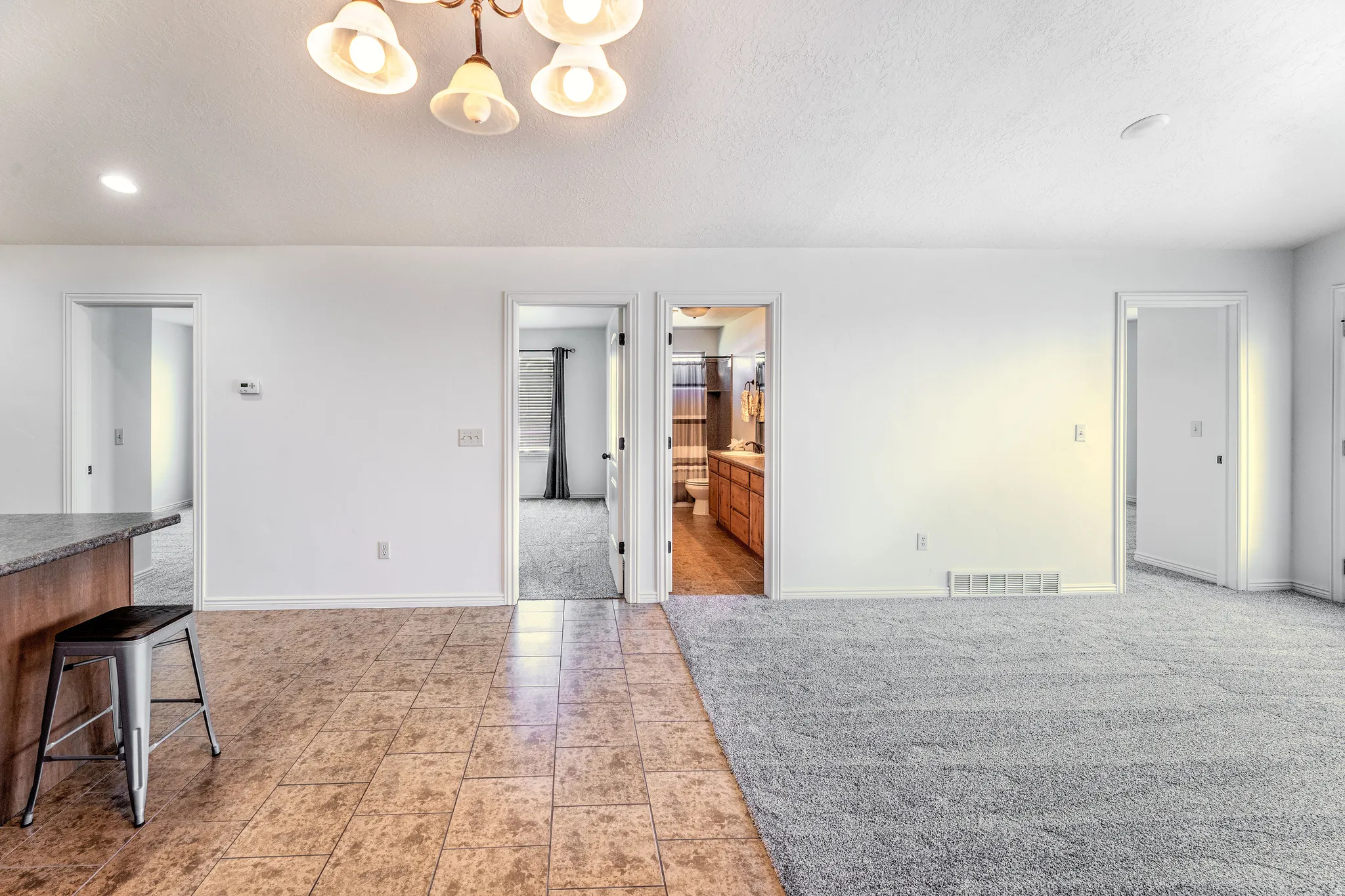 Unfurnished dining area with light tile patterned floors, light colored carpet, suspended lighting, and a textured ceiling