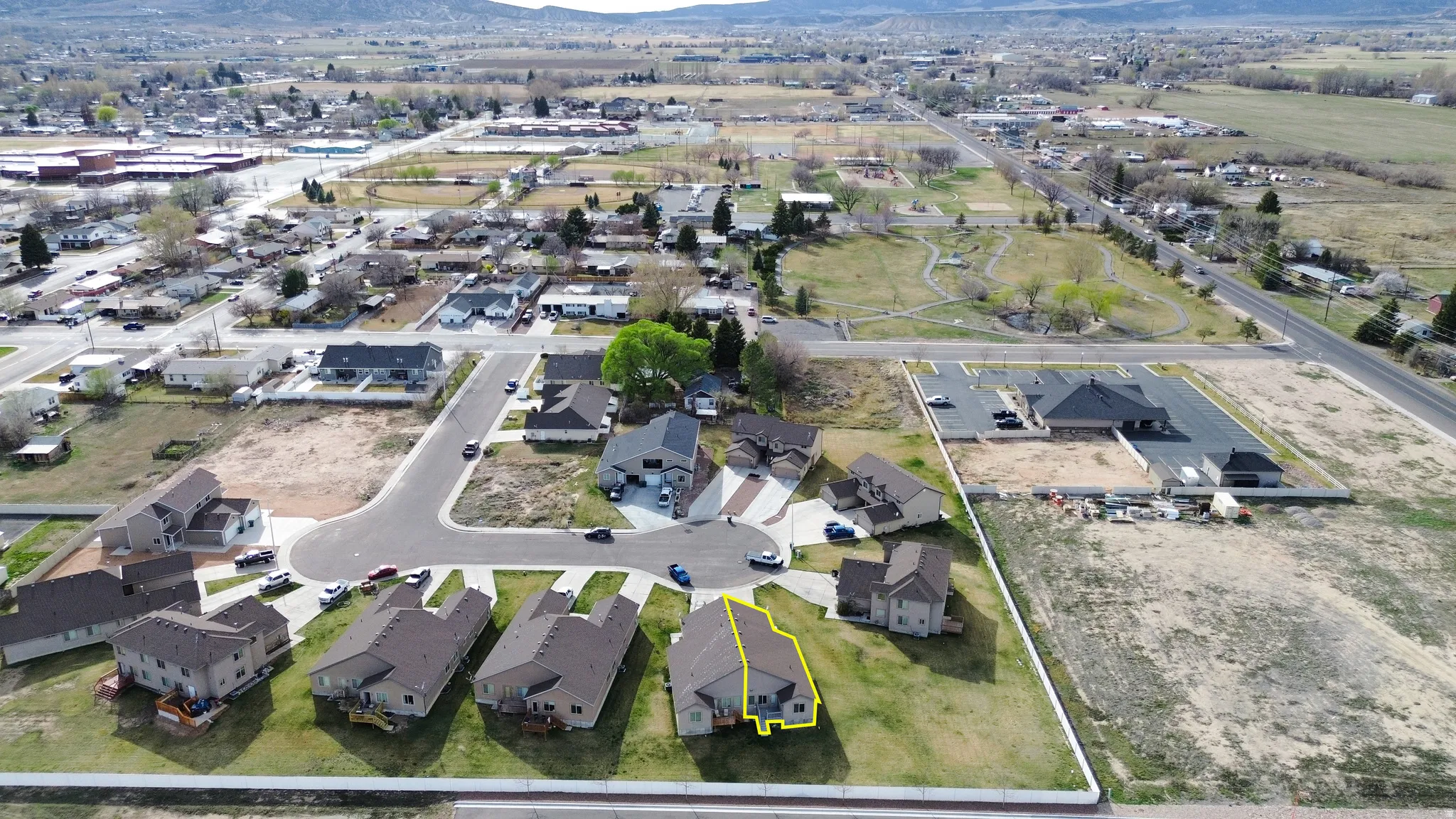 Aerial perspective of suburban area with property parcel outlined and mountains