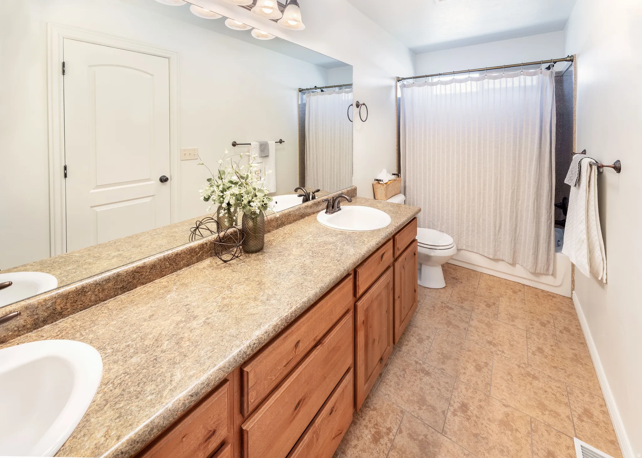 Bathroom featuring double vanity and shower / bath combo with shower curtain