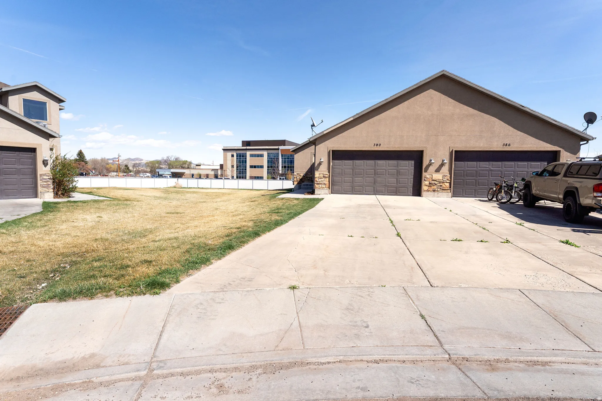 View of front facade featuring driveway, stone siding, stucco siding, and an attached garage