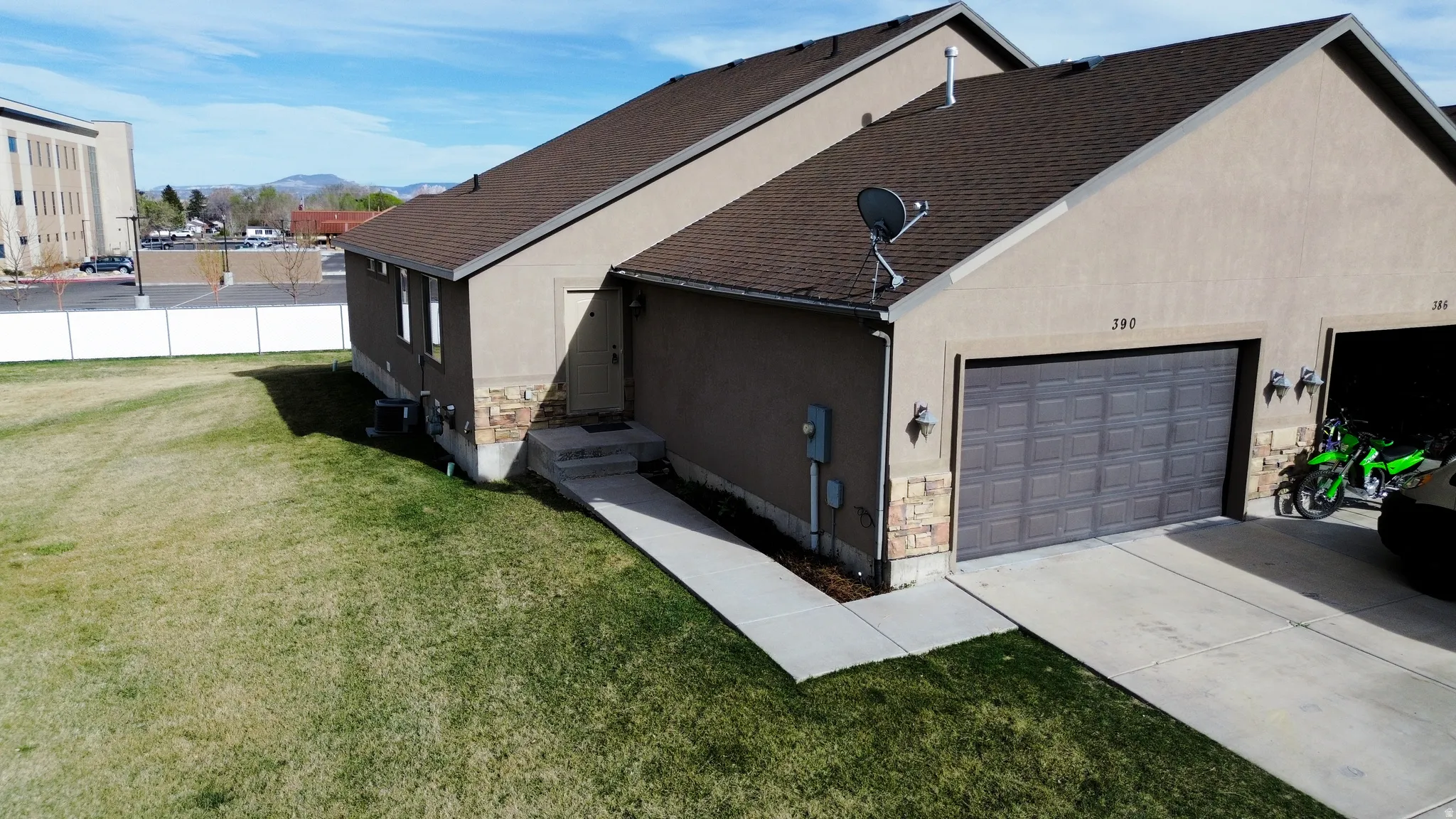 View of side of property with stucco siding, stone siding, concrete driveway, an attached garage, and a mountain view