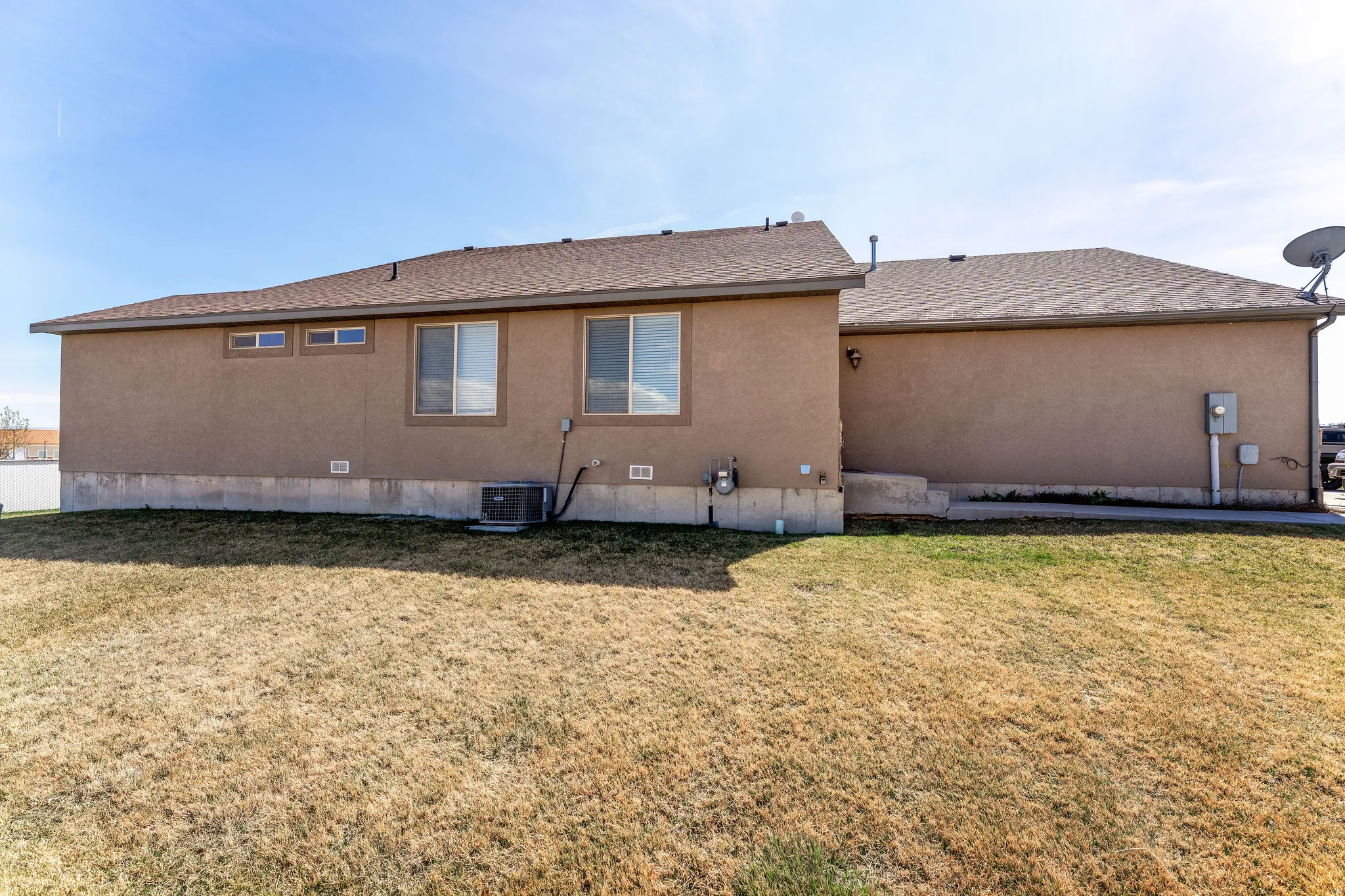 Back of property featuring a yard, roof with shingles, and stucco siding