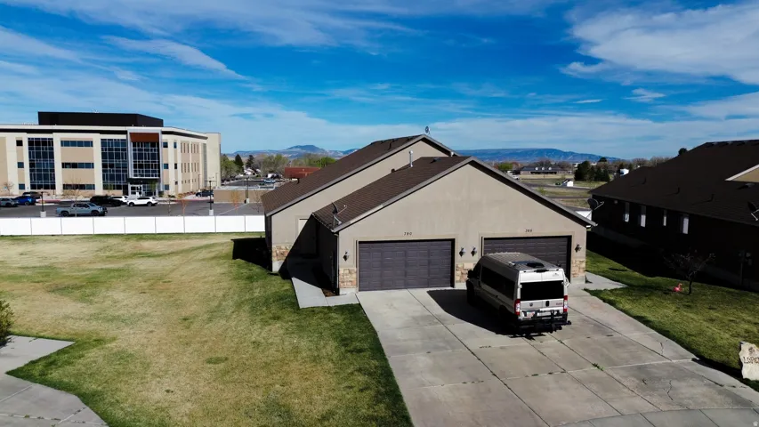 Ranch-style home with a garage, concrete driveway, a mountain view, and stone siding