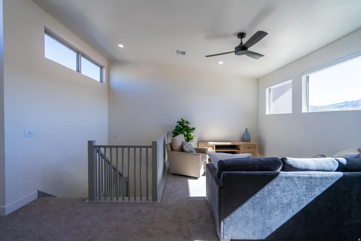 Carpeted living area featuring ceiling fan and recessed lighting