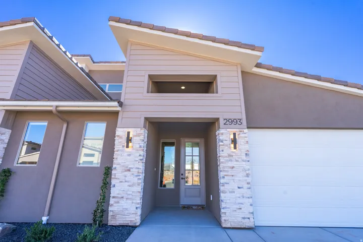 Entrance to property with stone siding, stucco siding, french doors, and an attached garage