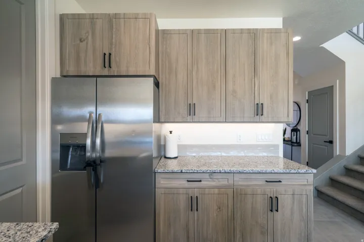 Kitchen featuring light stone counters and stainless steel fridge with ice dispenser