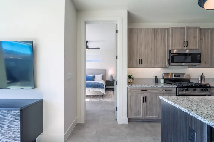 Kitchen featuring light stone countertops, stainless steel appliances, a ceiling fan, and wood finish cabinetry
