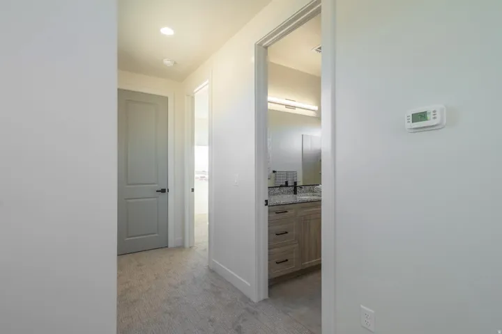 Corridor with light colored carpet and baseboards