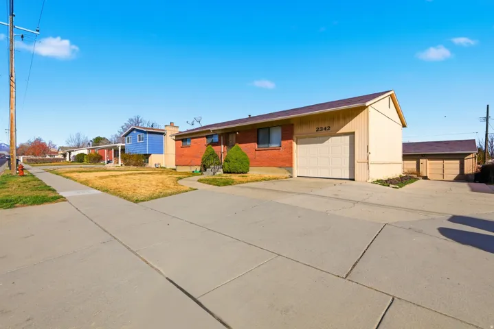 View of front of property featuring driveway, brick siding, an attached garage, and a front yard
