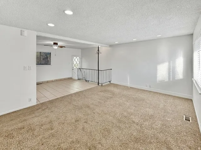 Unfurnished room featuring light carpet, ceiling fan, recessed lighting, a textured ceiling, and light tile patterned flooring