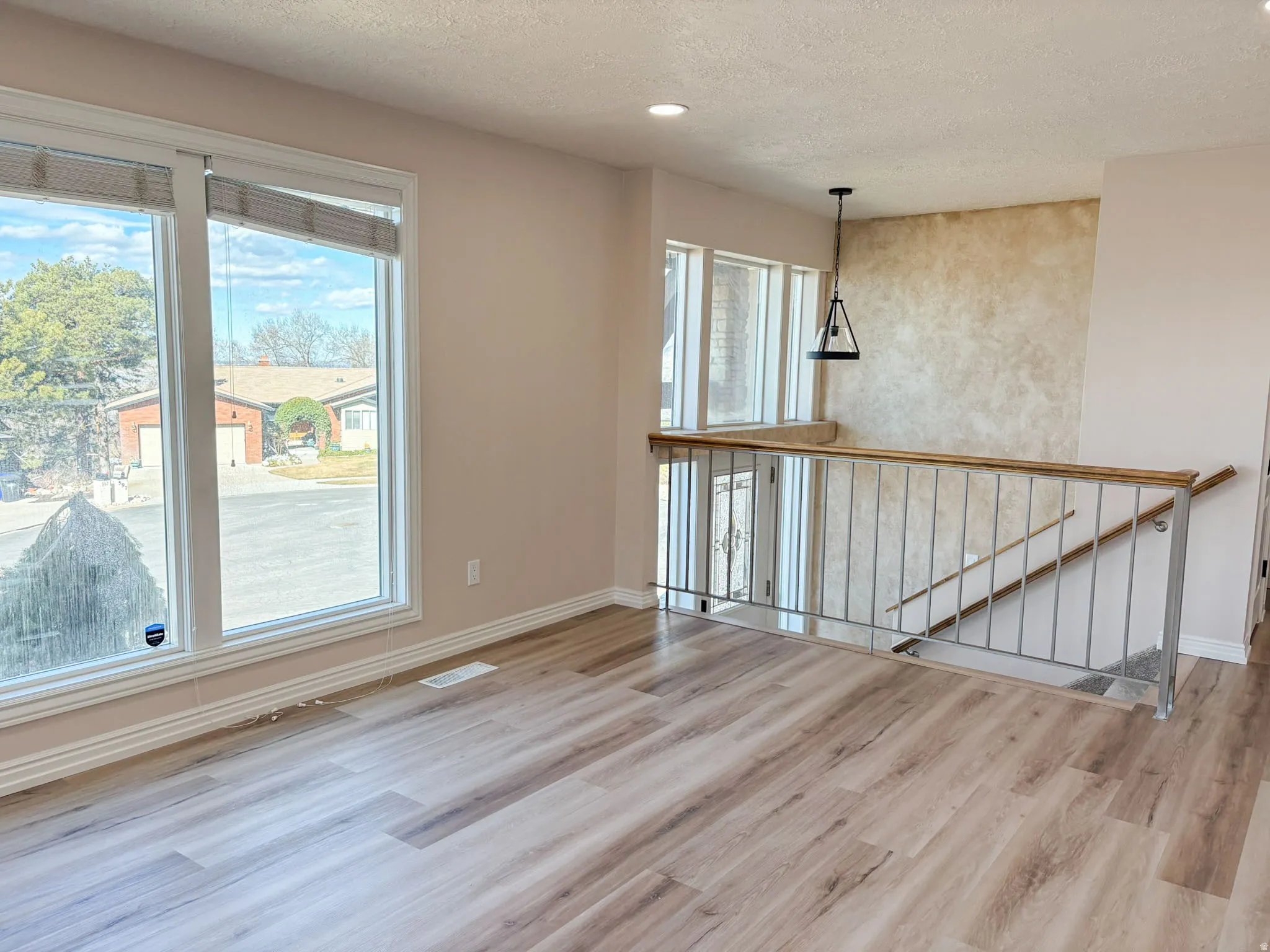 Unfurnished living room featuring light wood-style flooring, a textured ceiling, and recessed lighting