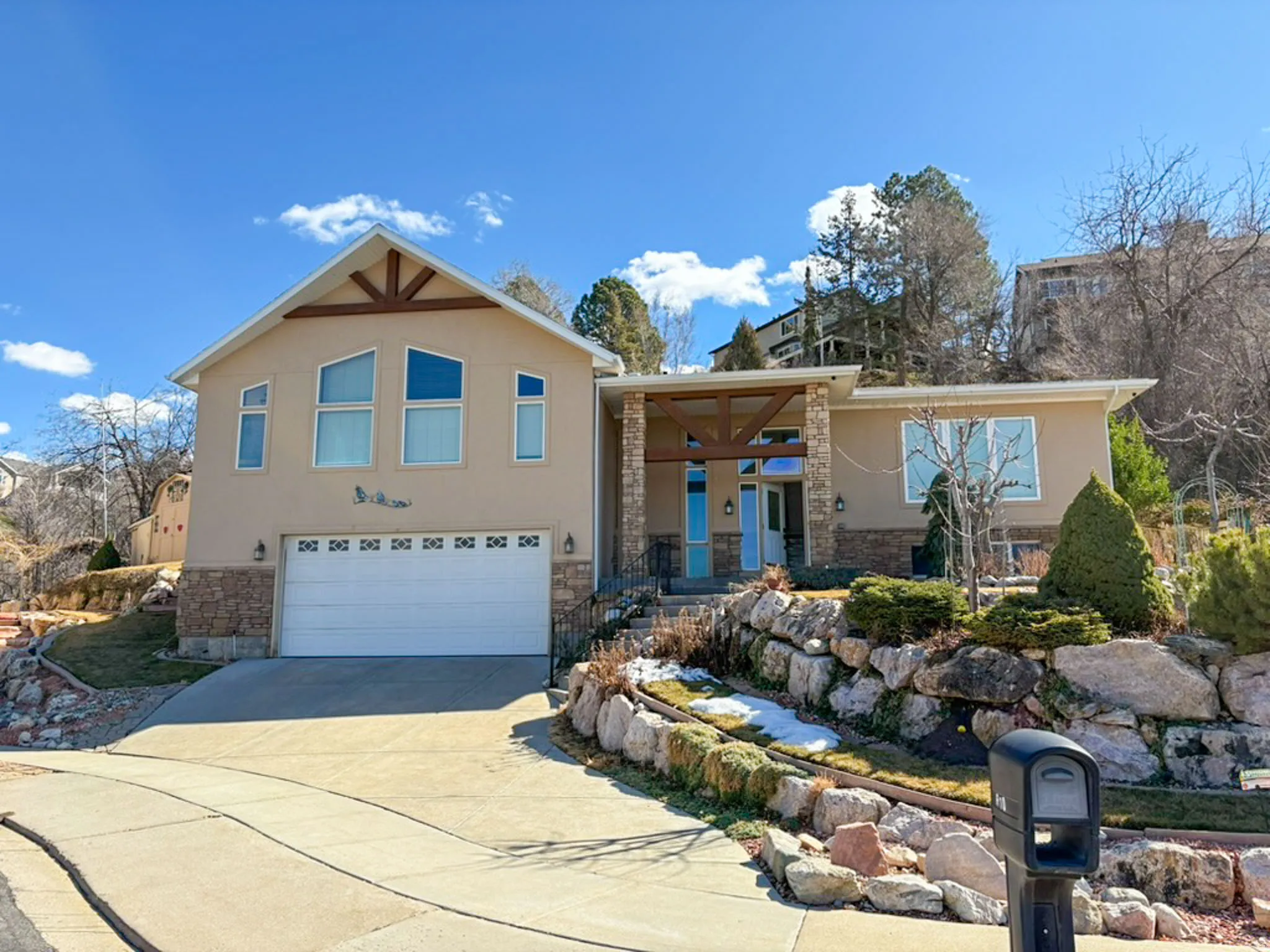 View of front of property featuring stone siding, covered porch, a garage, and driveway