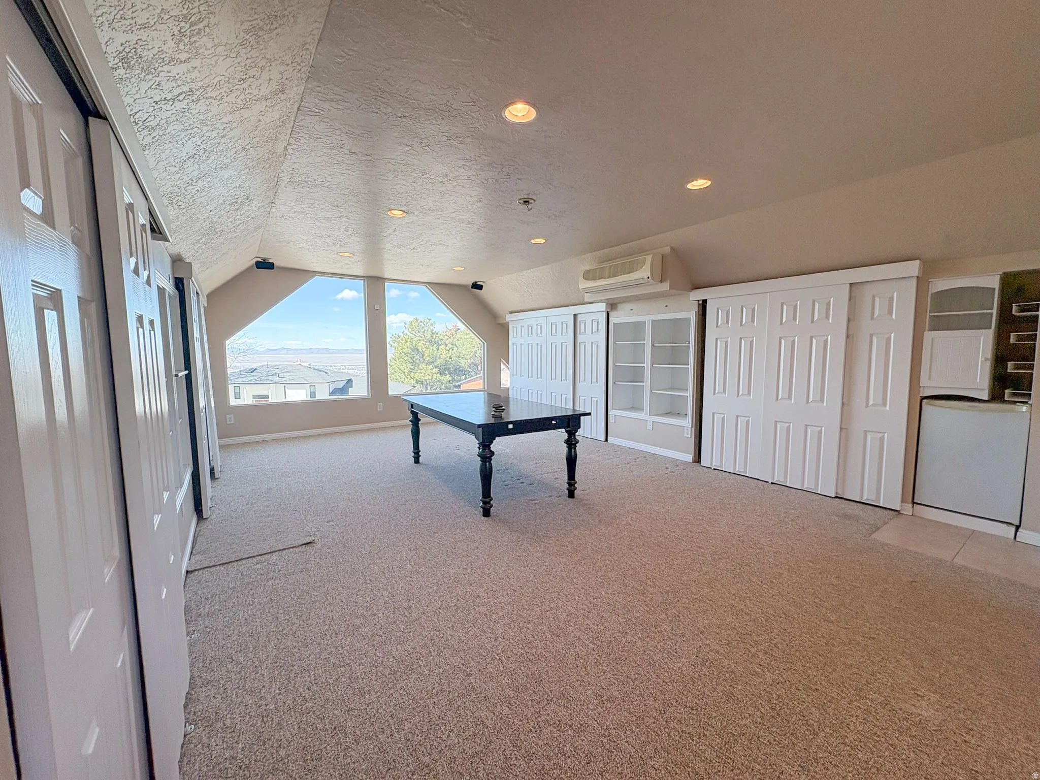 Recreation room with a textured ceiling, light carpet, and recessed lighting.  Loft above detached garage