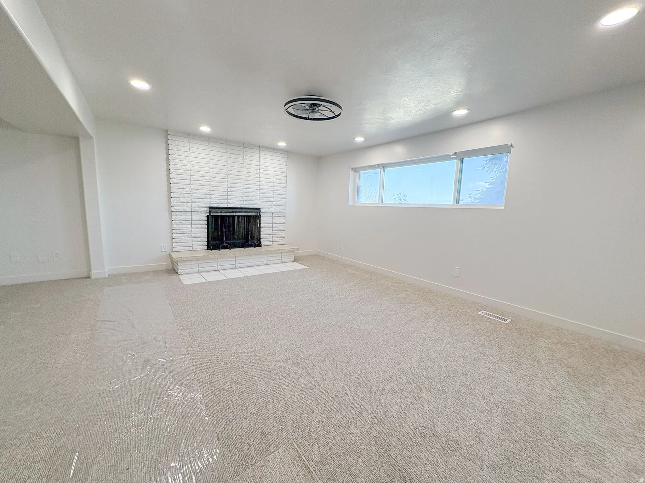 Unfurnished living room with carpet floors, a brick fireplace, and recessed lighting