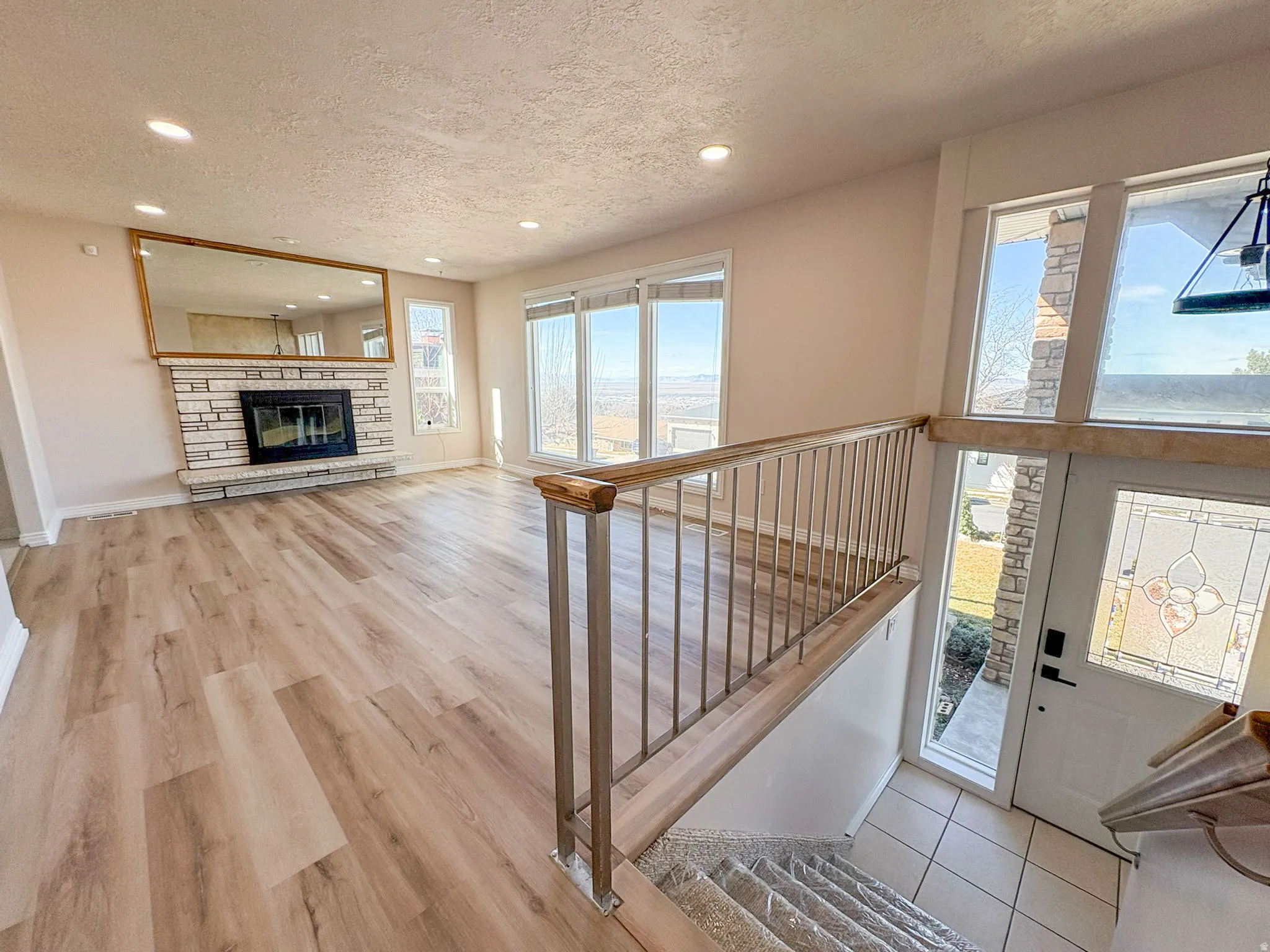 Foyer with a textured ceiling, recessed lighting, a stone fireplace, and light wood-type flooring