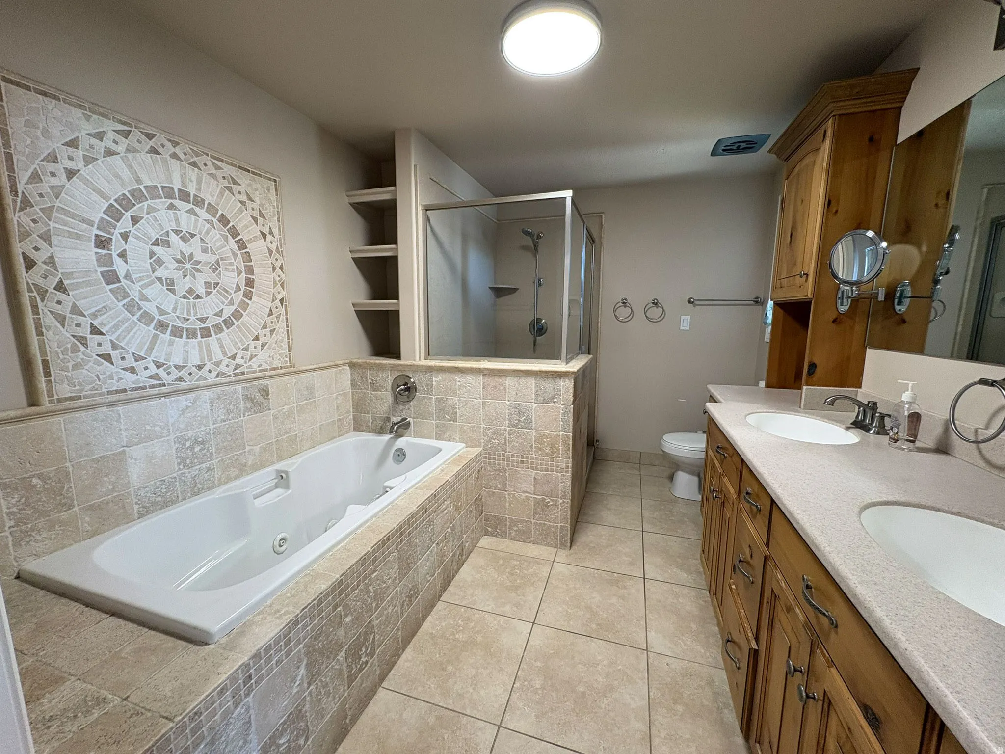 Full bath with double vanity, a stall shower, light tile patterned flooring, and a  jetted tub