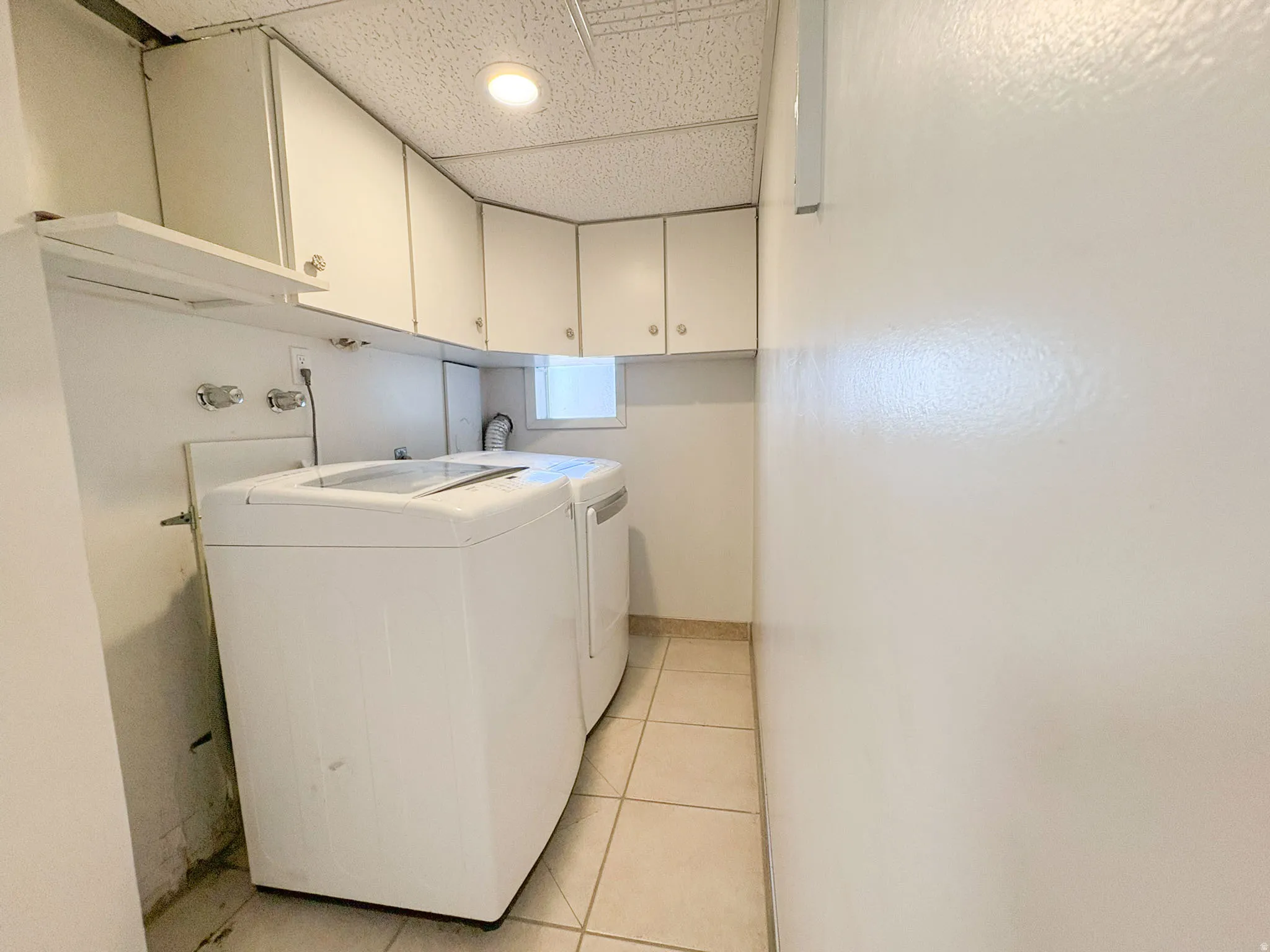 Laundry room with light tile patterned flooring, independent washer and dryer, cabinet space, and a drop ceiling