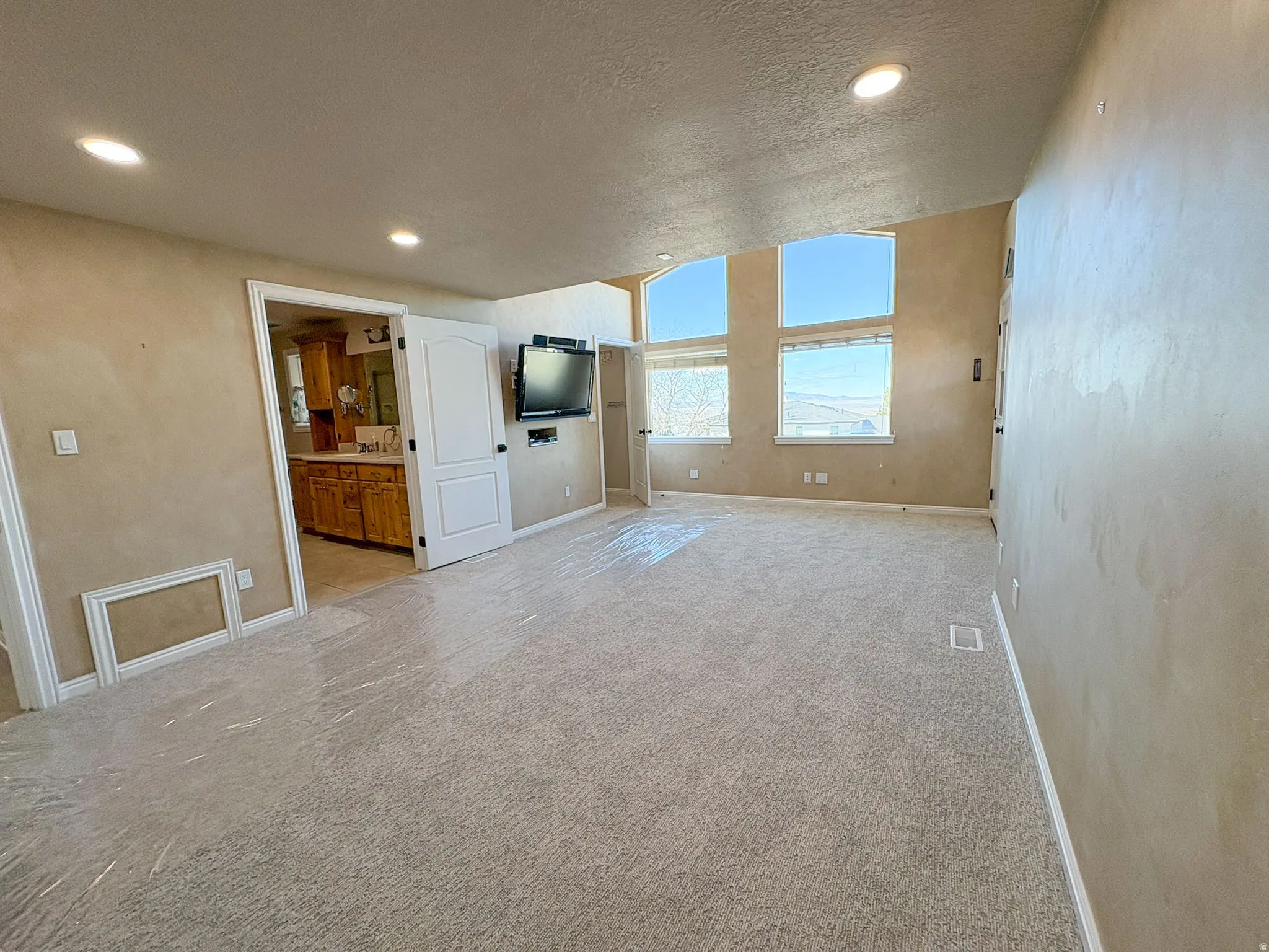 Unfurnished main bedroom featuring a textured ceiling, recessed lighting, and light carpet with view of valley and lake