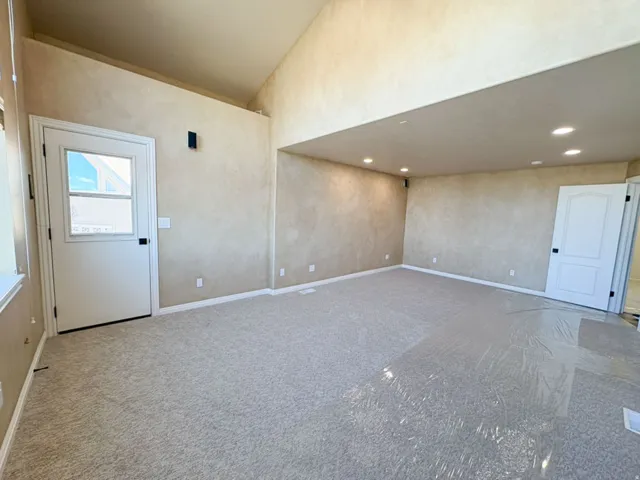 Carpeted empty room featuring lofted ceiling and recessed lighting