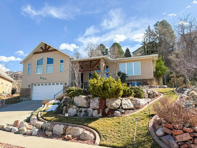 View of front of house featuring stone siding, an attached garage, stucco siding, and concrete driveway