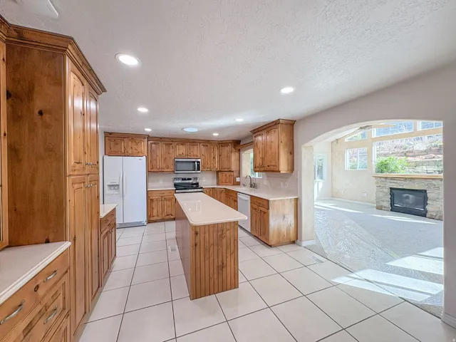 Kitchen featuring wood finish cabinetry, stainless steel appliances, a kitchen island, a textured ceiling, and recessed lighting