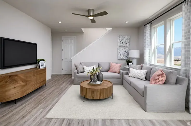 Living area featuring light wood-style floors, ceiling fan prewire, half wall at stairs and loft, and recessed lighting. Pictures are of a model home only! This home may feature different finishes than what is pictured.
