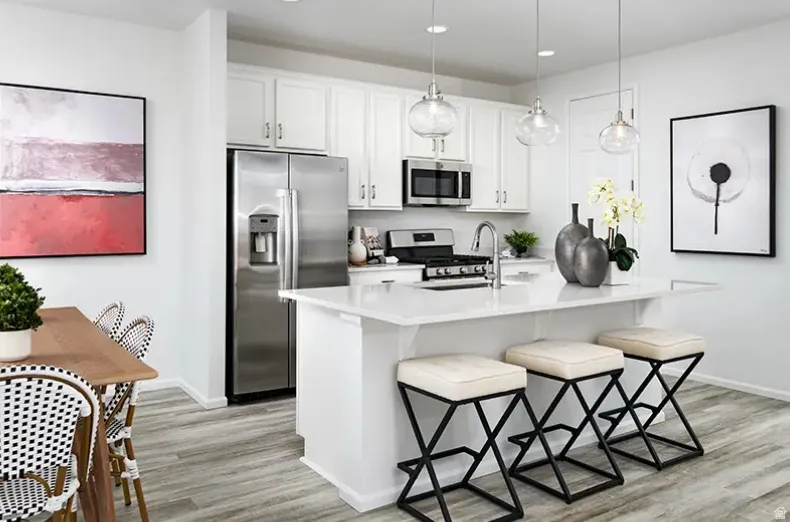 Kitchen featuring stainless steel appliances, white cabinets, a breakfast bar, and a kitchen island with sink. Pictures are of a model home only! This home may feature different finishes than what is pictured.