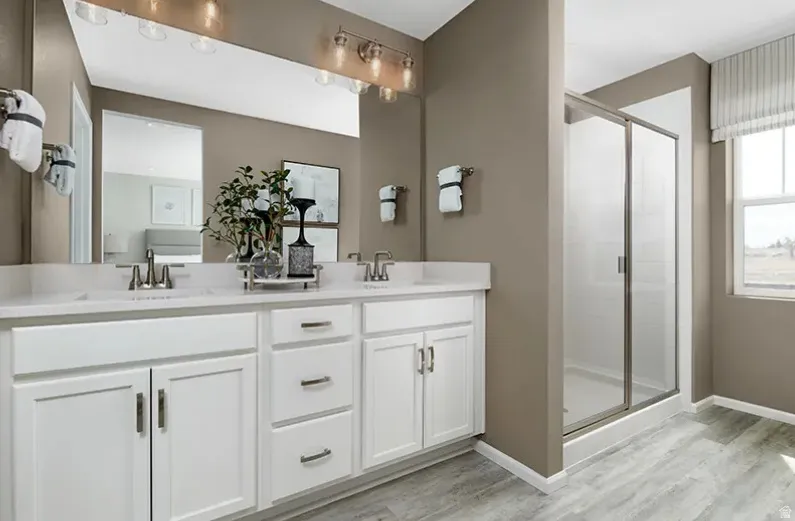 Primary Bathroom featuring double vanity, a stall shower, and light wood-style flooring. Pictures are of a model home only! This home may feature different finishes than what is pictured.