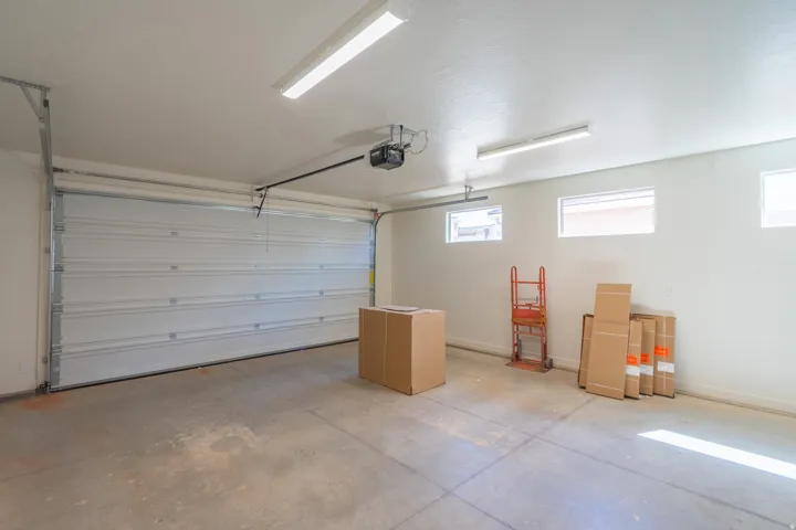 Spacious garage with a sectional overhead door, automatic opener, and concrete flooring