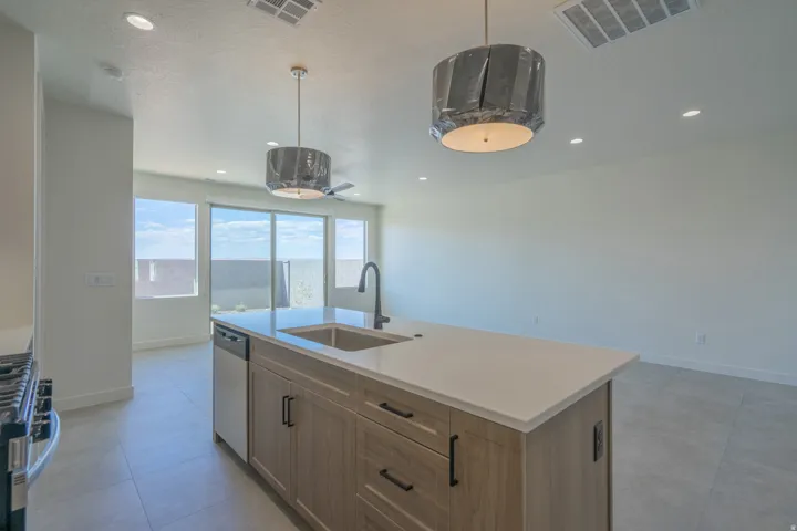 Kitchen island with a light-colored countertop, integrated sink, and dark faucet