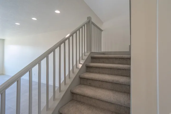 Carpeted staircase with light gray railing and balusters