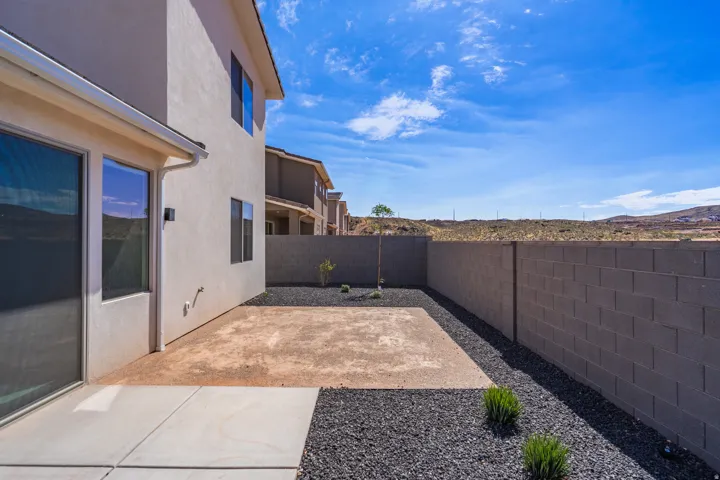 Exterior patio area featuring a concrete slab, dark gravel landscaping, and a block wall perimeter