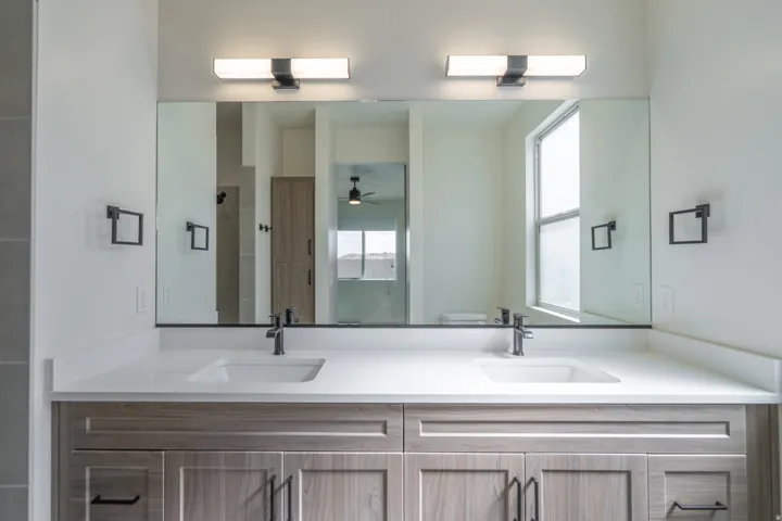 Dual vanity with integrated sinks, quartz countertop, and wood-finish cabinetry