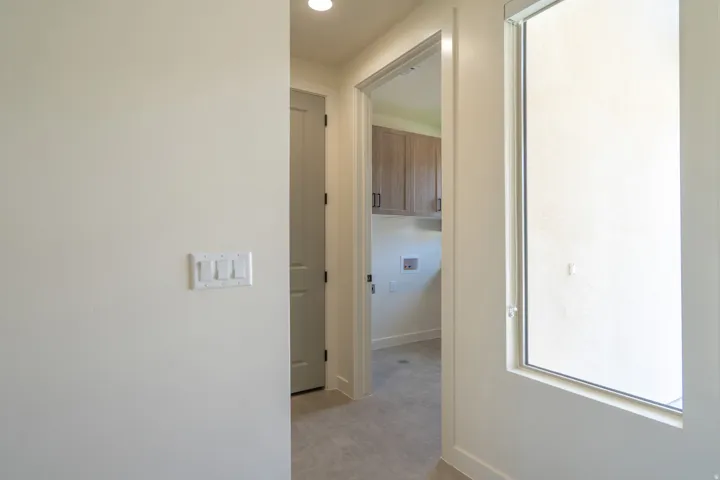 Laundry area with light wood-finish cabinetry, a utility sink connection, and tile flooring