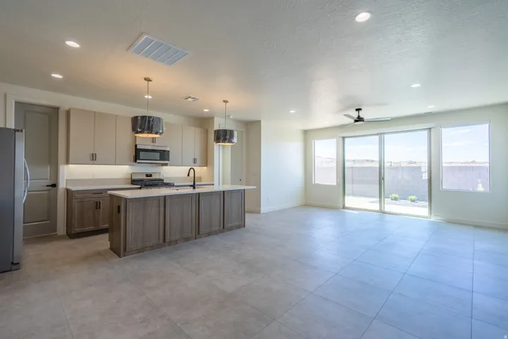 Spacious open-concept area featuring a kitchen island, recessed lighting, and large format tile flooring