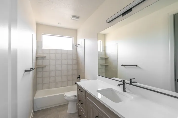 Bathroom featuring a large vanity with an integrated rectangular sink, a wide mirror, and a linear overhead light fixture