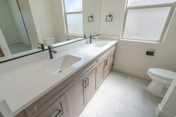 Dual undermount sinks set into a light-toned countertop, complemented by matte black faucets
