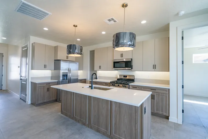 Modern kitchen featuring a large central island with a solid surface countertop, stainless steel appliances, contemporary cabinetry, and recessed lighting