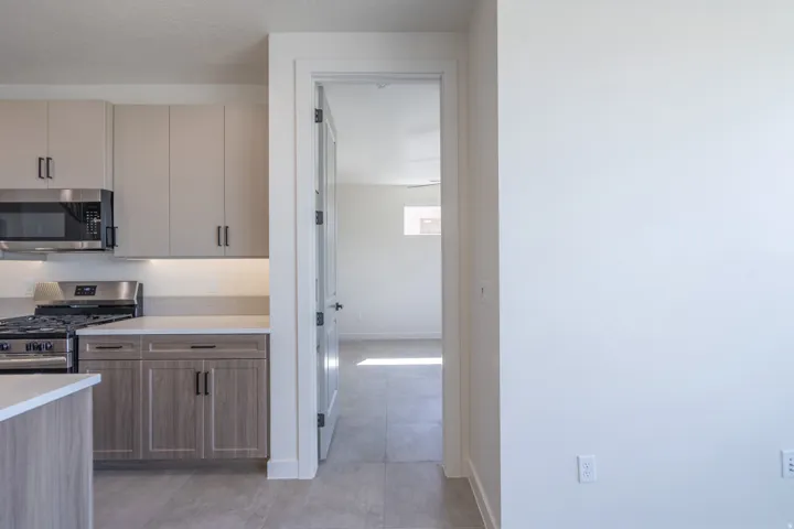 Contemporary kitchen featuring light-toned upper cabinetry, wood-finish lower cabinetry, and stainless steel appliances
