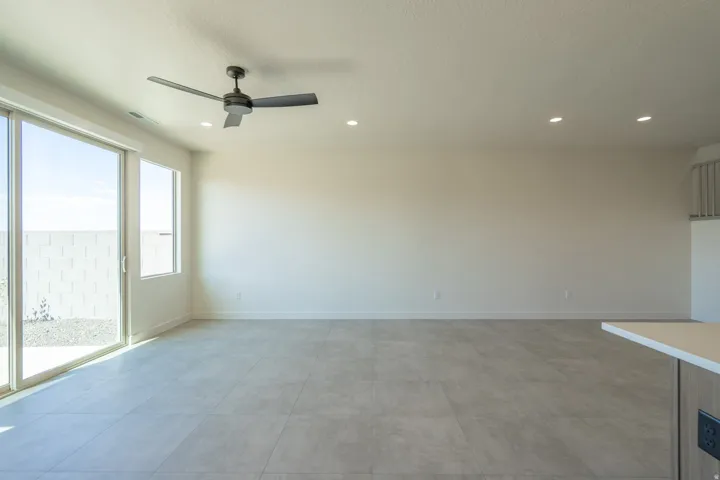 Spacious living area featuring large sliding glass doors, a single fixed window, recessed lighting, and a ceiling fan with integrated lighting