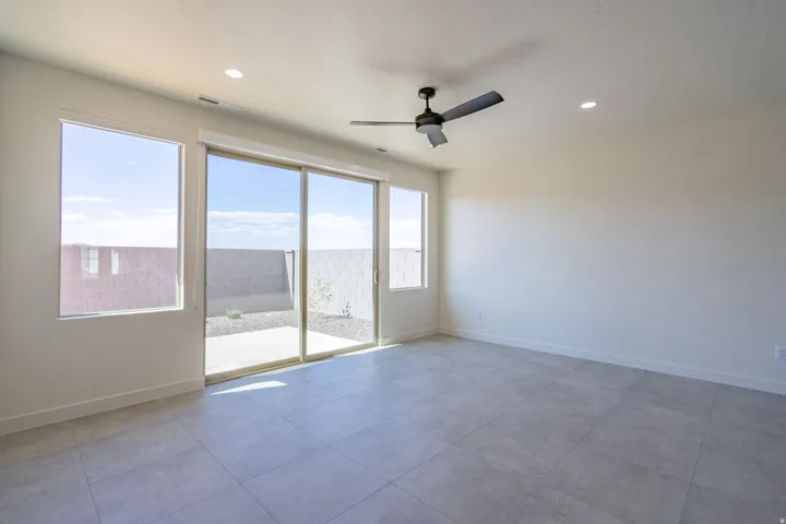 Spacious room featuring light gray tile flooring, a contemporary ceiling fan, and recessed lighting