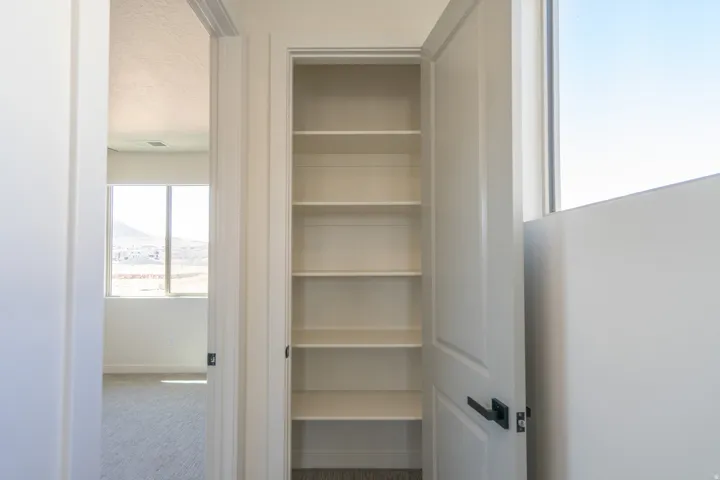 Built-in shelving with multiple levels, white paint finish, and contrasting dark hardware