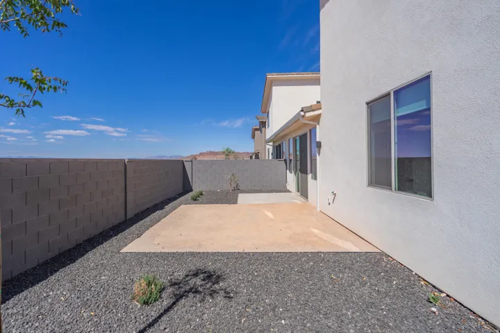 Private outdoor space featuring a concrete patio, dark aggregate landscaping, and a block fence perimeter