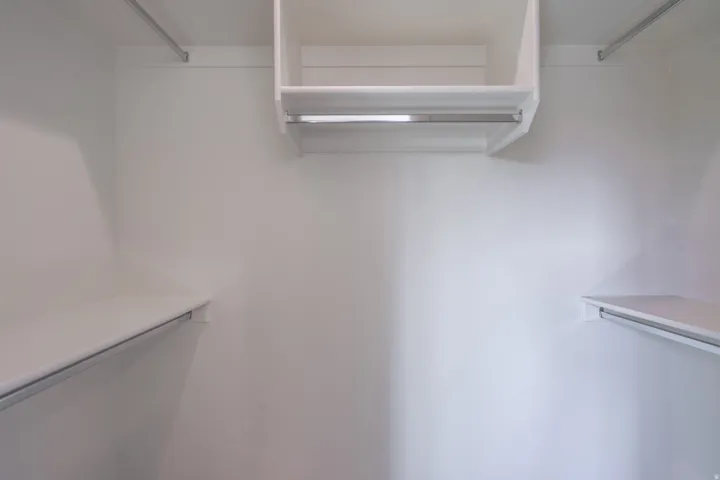 White painted walls with integrated shelving and chrome hanging rods