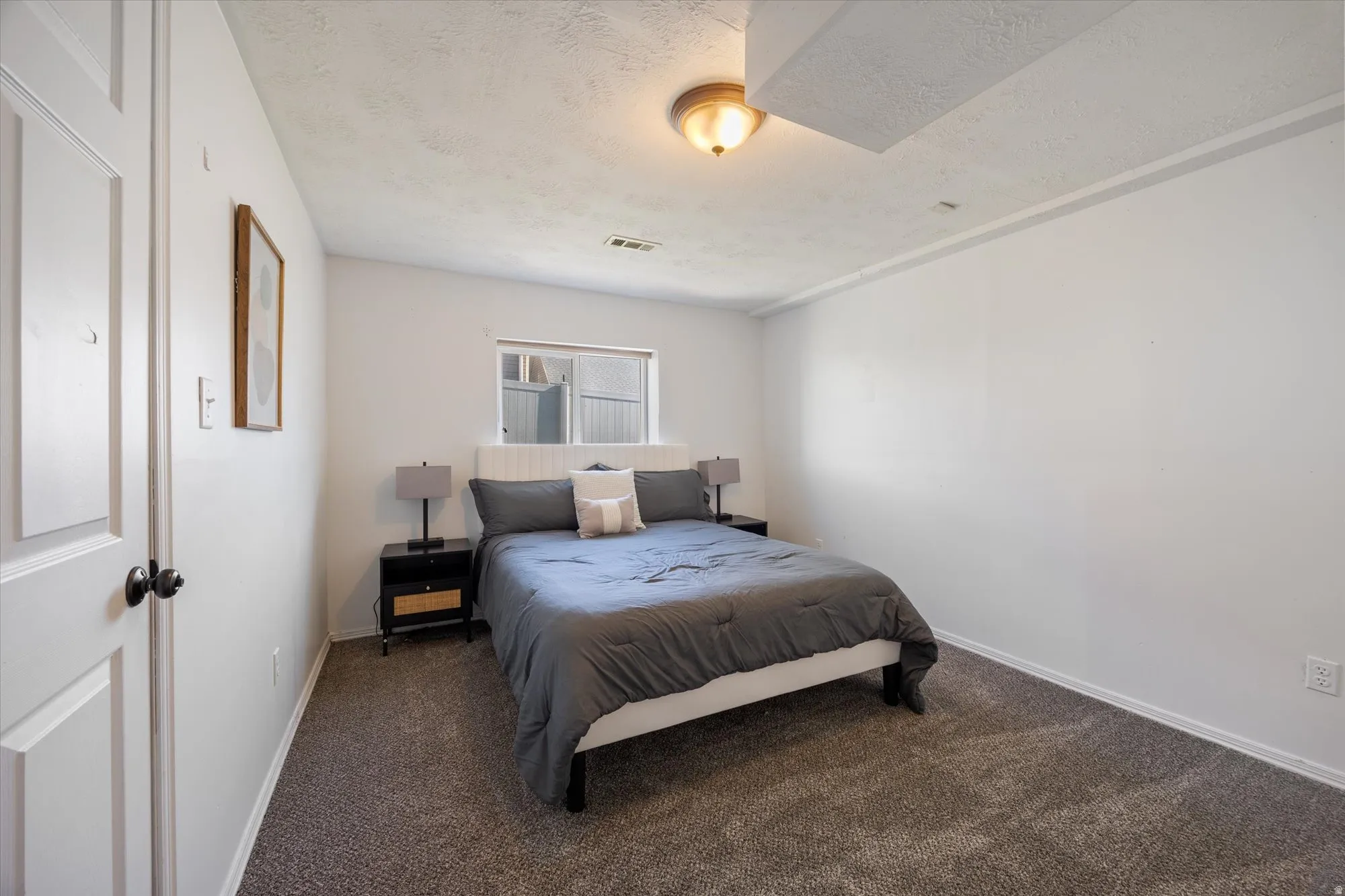Carpeted bedroom with a textured ceiling and baseboards