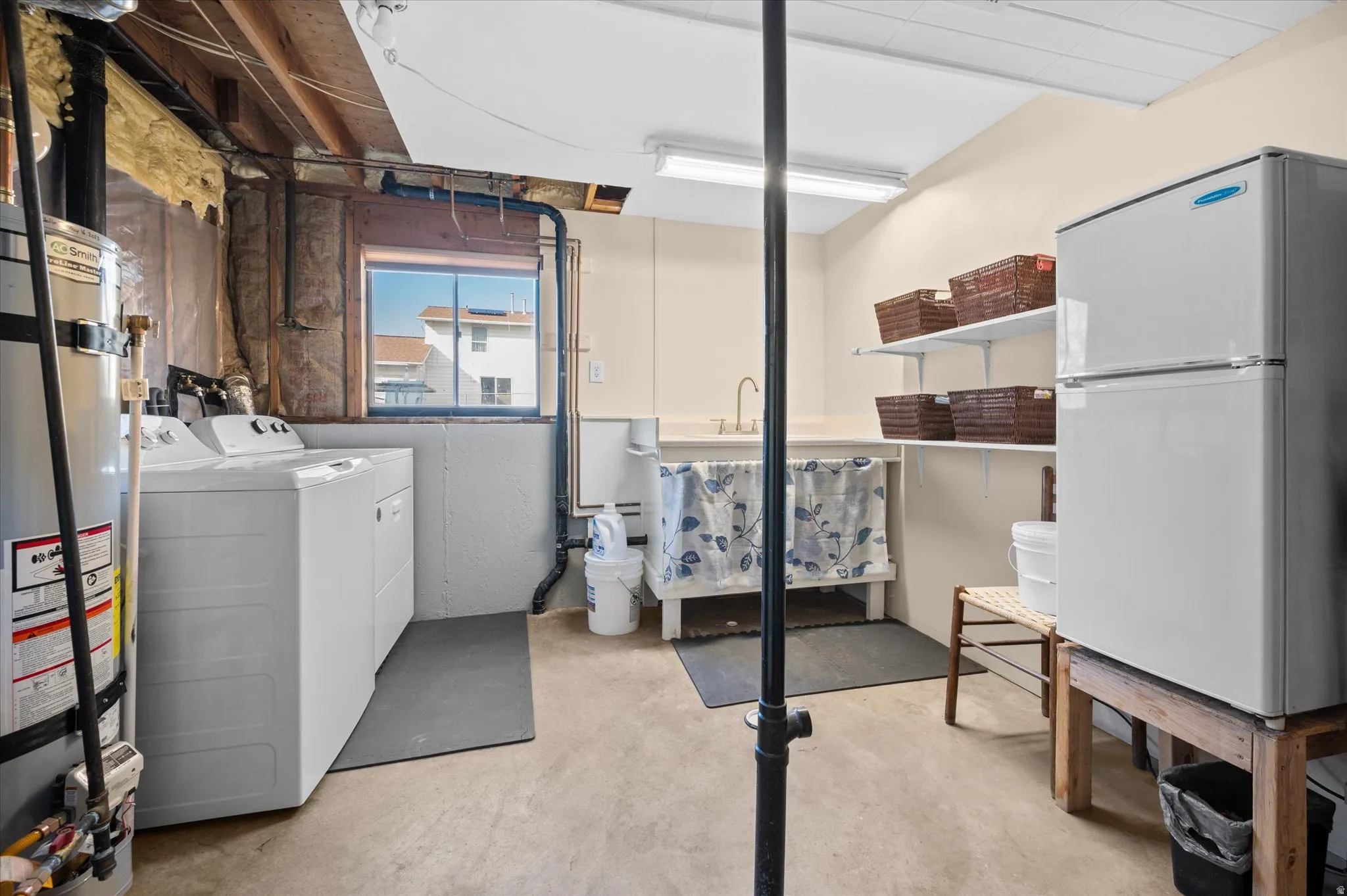 Laundry area featuring concrete flooring, secured water heater, and separate washer and dryer