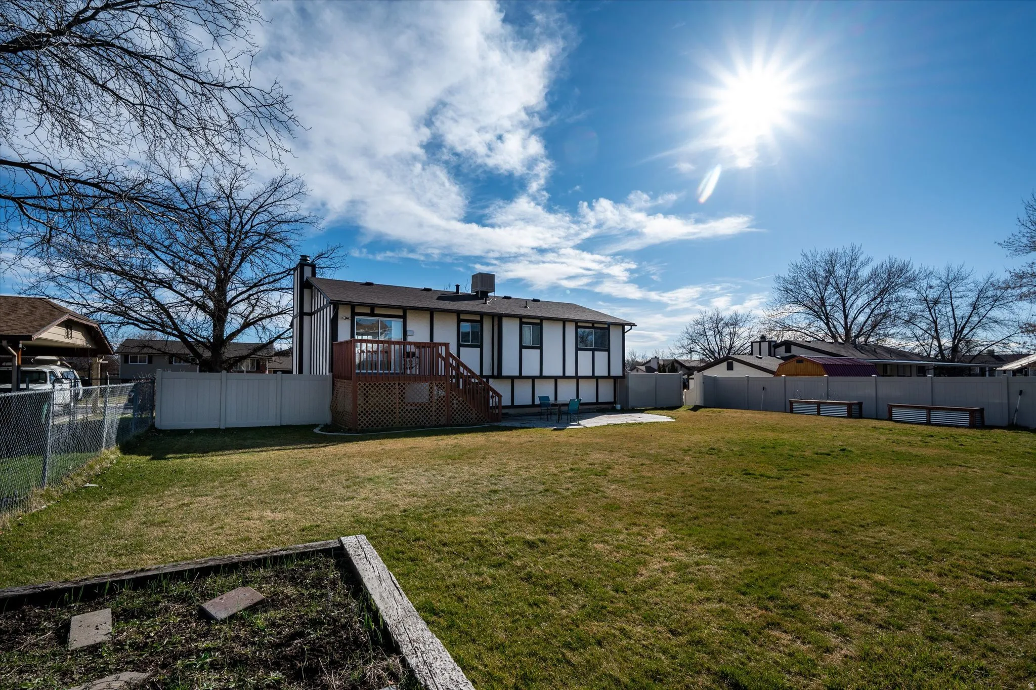 Rear view of property featuring a wooden deck, a fenced backyard, and a patio